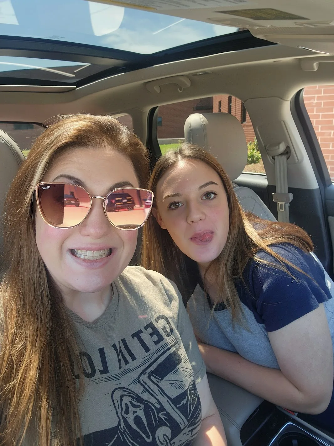 Ashley and Kayla making faces in a car selfie on the drive to move-in day